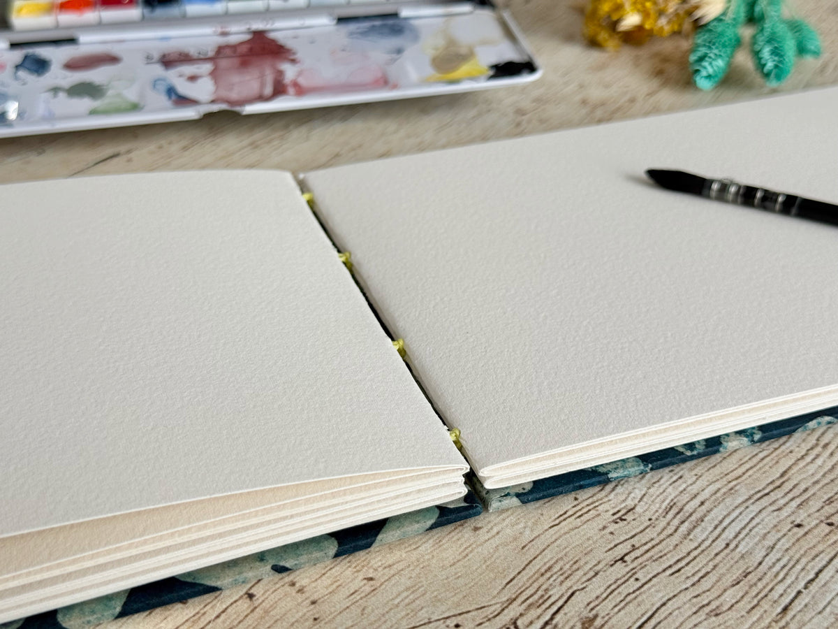 Carnet aquarelle Mikado bleu bien ouvert à plat grâce à sa reliure copte
