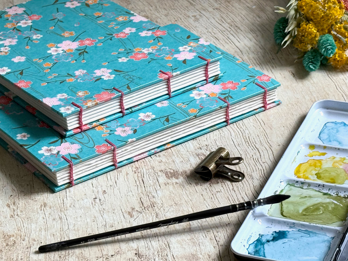 carnets d'aquarelle fait main, reliure copte visible sur la tranche des carnets